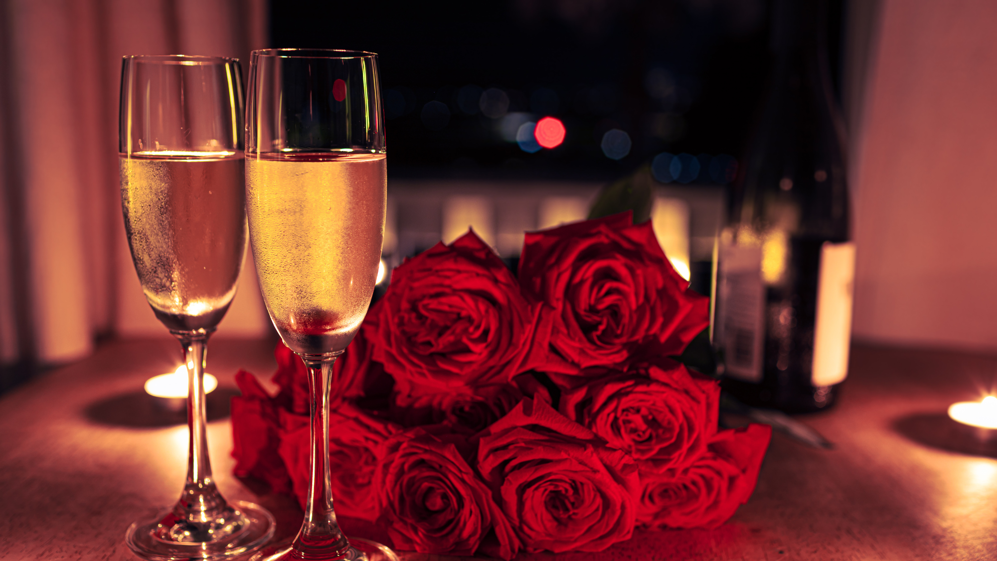 Romantic Valentine’s Day setup with champagne flutes, red roses, candlelight, and a cozy evening atmosphere in a vacation rental.